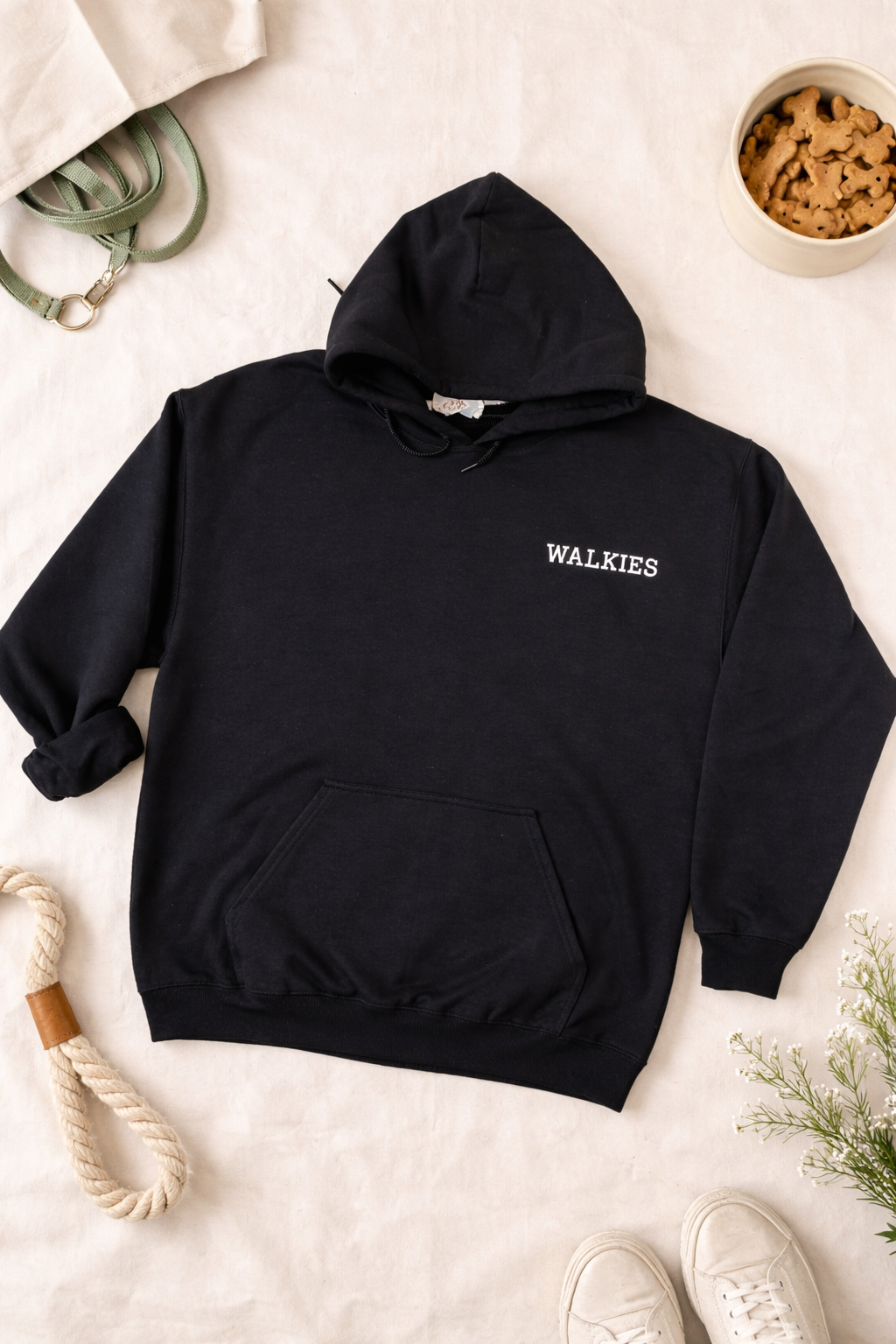 Black hoodie with 'WALKIES' text on a light surface with accessories.