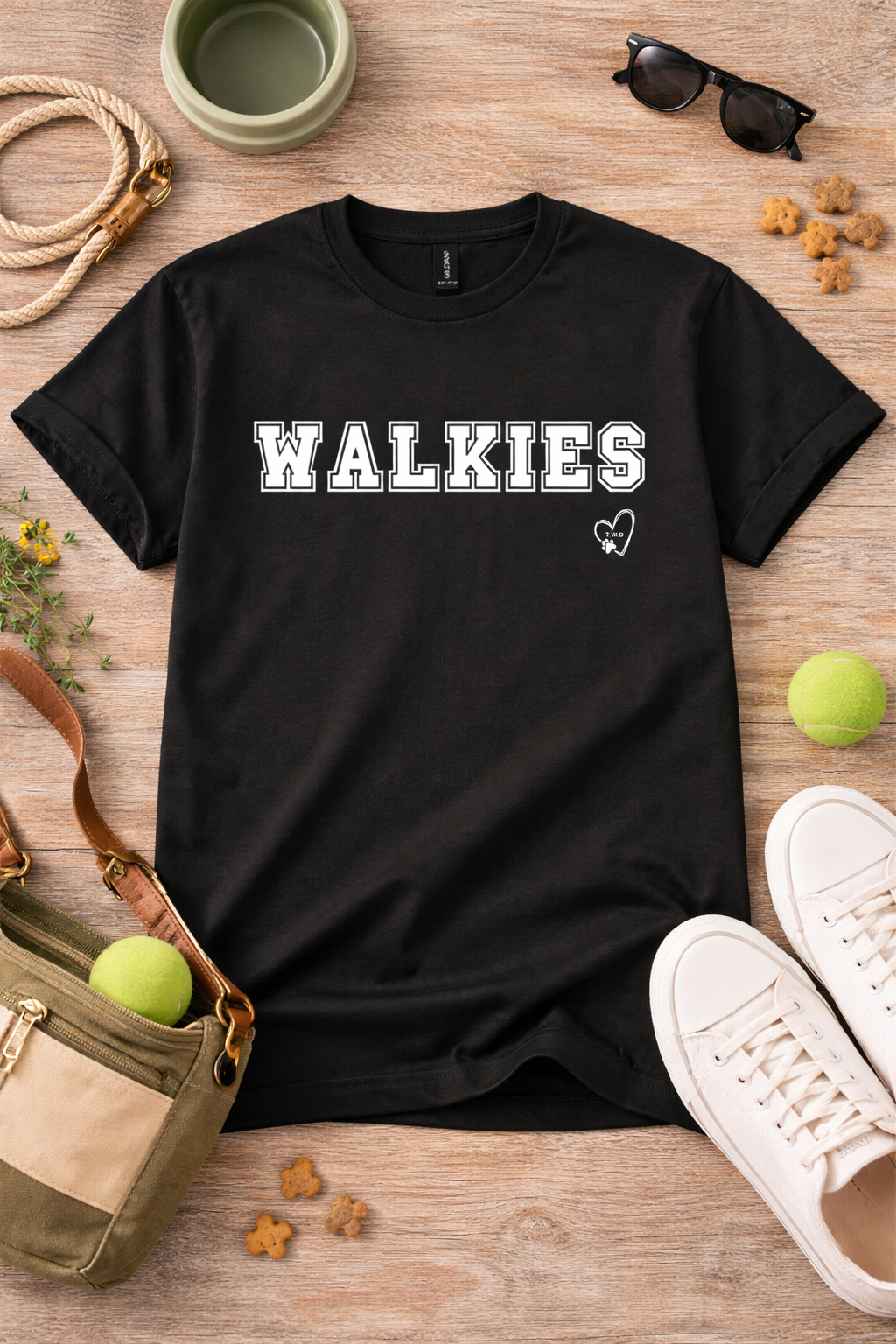 Black t-shirt with 'WALKIES' text on a wooden surface with accessories.