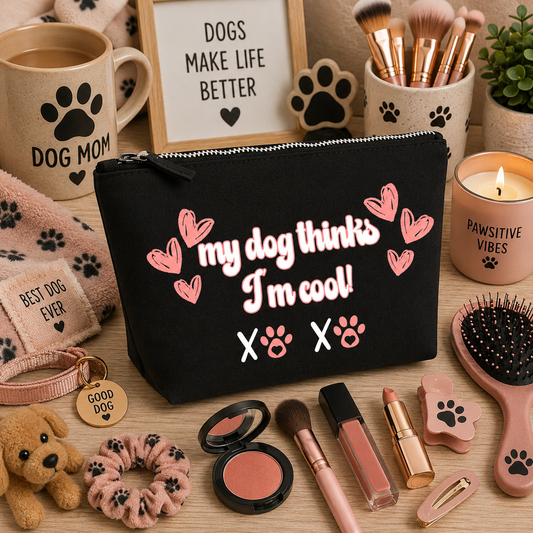 Black canvas makeup bag featuring the playful "My Dog Thinks I'm Cool!" design with pink hearts and paw prints, displayed on a cosy dog-themed vanity background with makeup brushes, lipstick, blush, hair accessories, paw-print décor, and cute dog lover accessories. Perfect for dog mums and beauty enthusiasts.