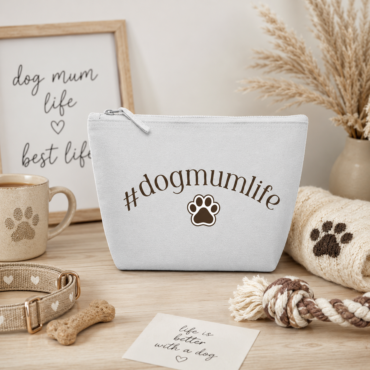 Grey zip travel pouch featuring the "#dogmumlife" slogan with a paw print design, styled in a cosy dog mum setting with dog treats, a collar, and dog-themed accessories. Perfect cosmetic and travel bag for dog lovers.