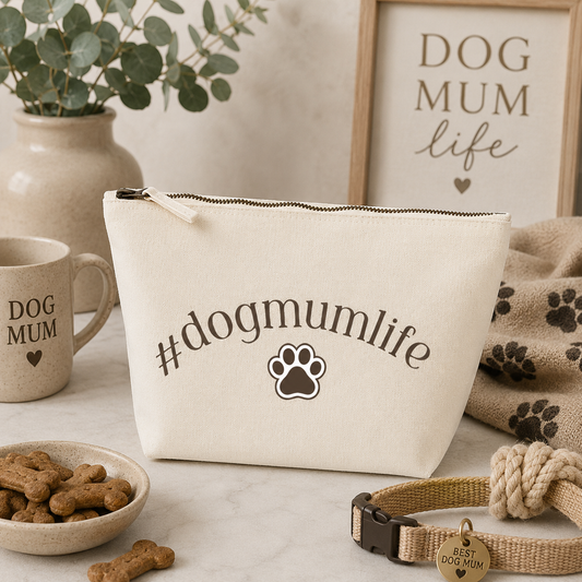 Large cream travel bag featuring the '#dogmumlife' design with a paw print, displayed on a cosy dog mum themed background with dog treats, rope toy, collar, mug and neutral home décor. Perfect as a cosmetic, toiletry or travel pouch for dog lovers.