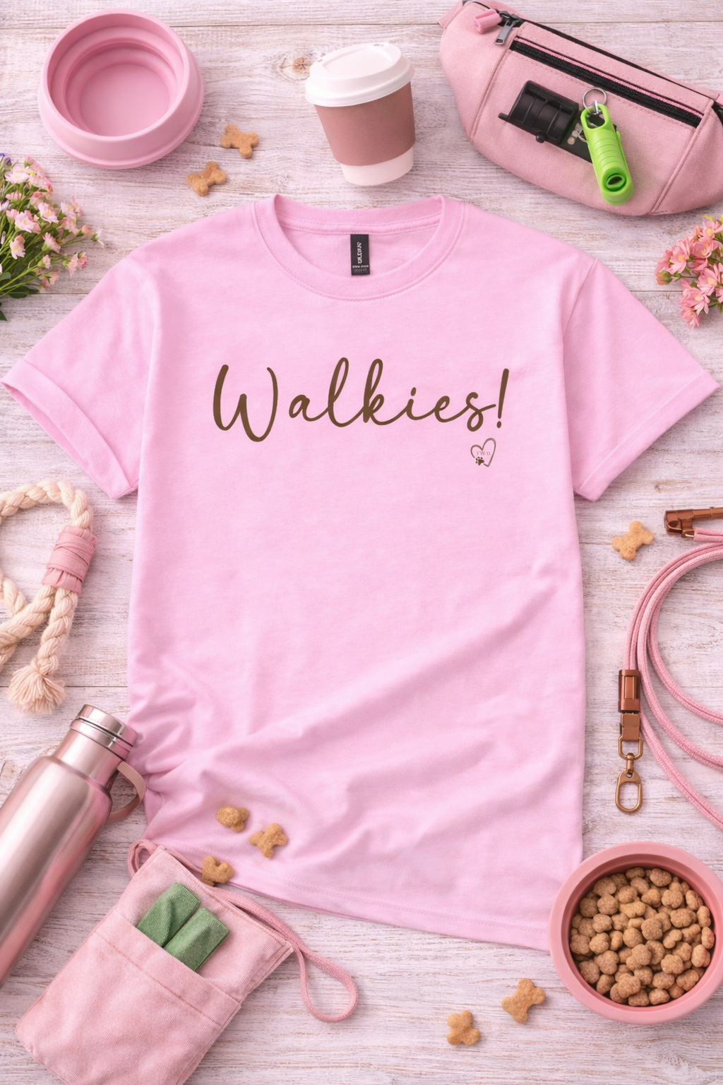 Pink t-shirt with 'Walkies!' text on a wooden surface with pet accessories.