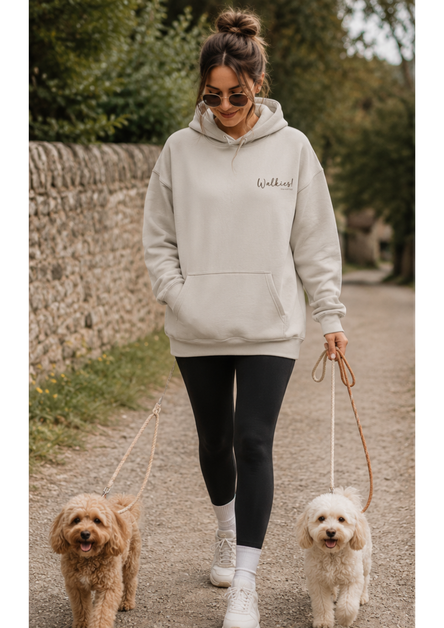 Female dog owner walking two small dogs wearing a sand Walkies hoodie by That Woofin Dog, featuring a minimalist front chest design and relaxed fit.
