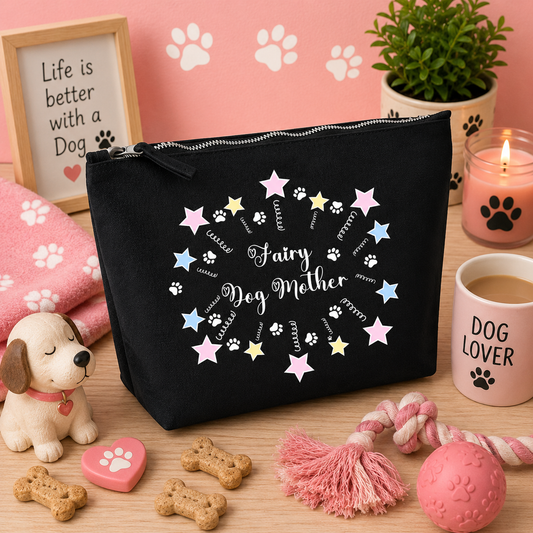 Black cosmetic travel bag featuring a whimsical "Fairy Dog Mother" design with pastel stars and paw prints, displayed on a cosy pink dog-themed background with dog toys, paw-print décor, candles, dog treats, and accessories, making a perfect gift for dog mums and dog lovers.