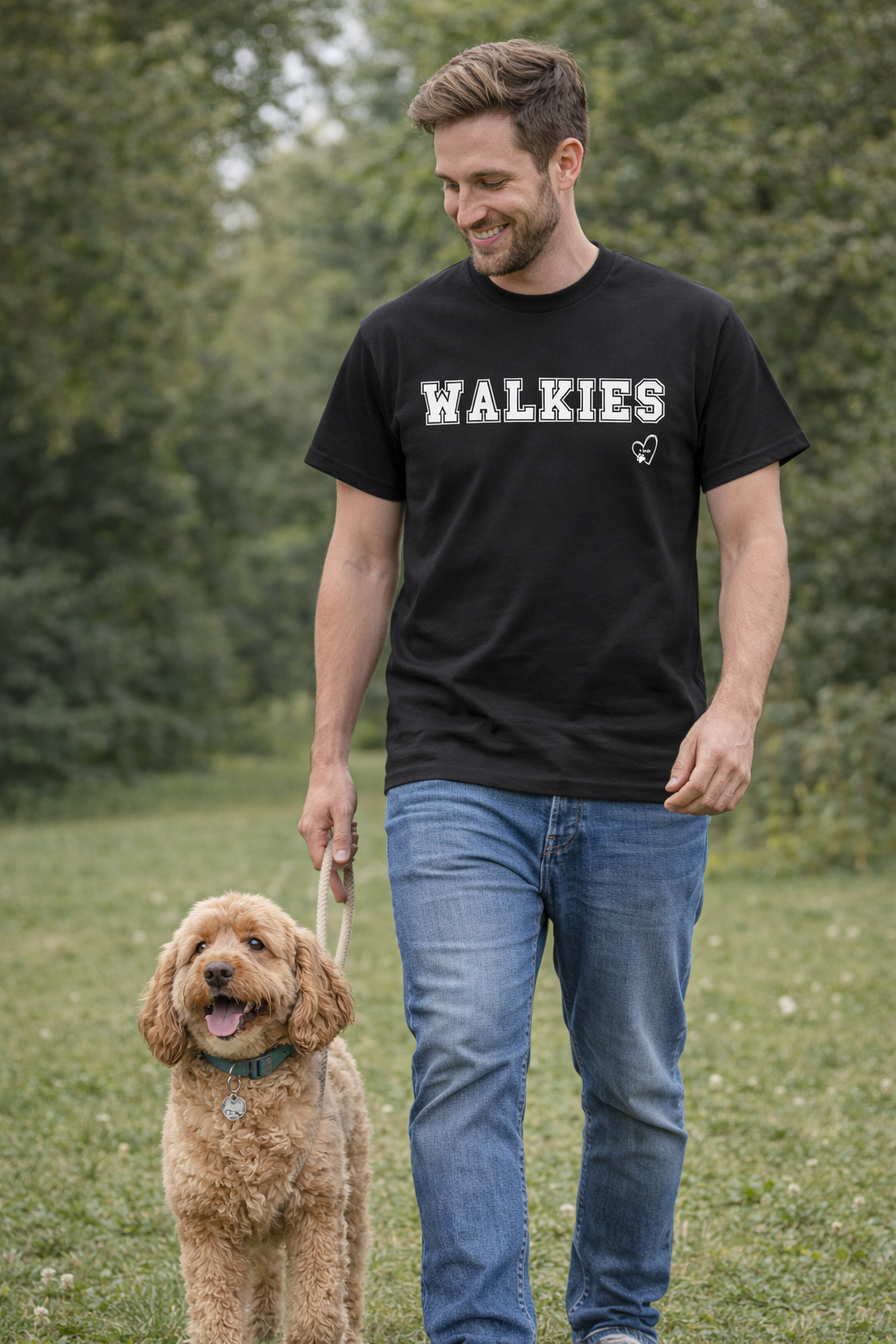 Man walking a dog in a field wearing a black t-shirt with 'WALKIES' text.