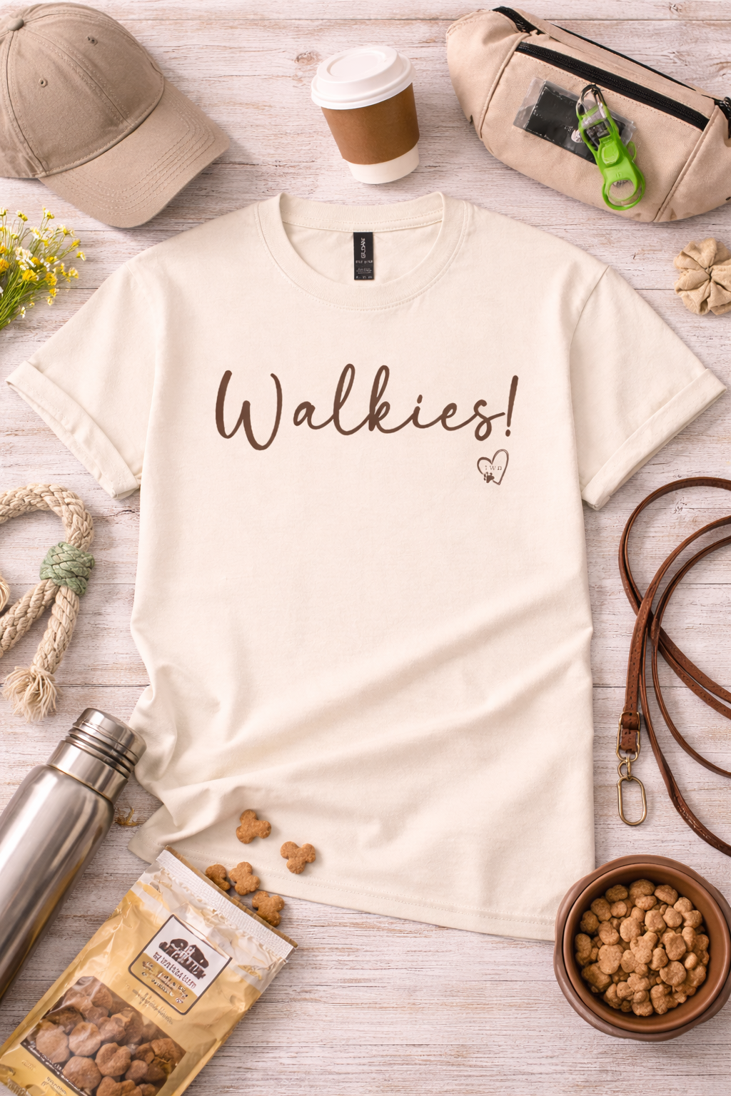 Natural t-shirt with 'Walkies!' text on a wooden surface with pet accessories.