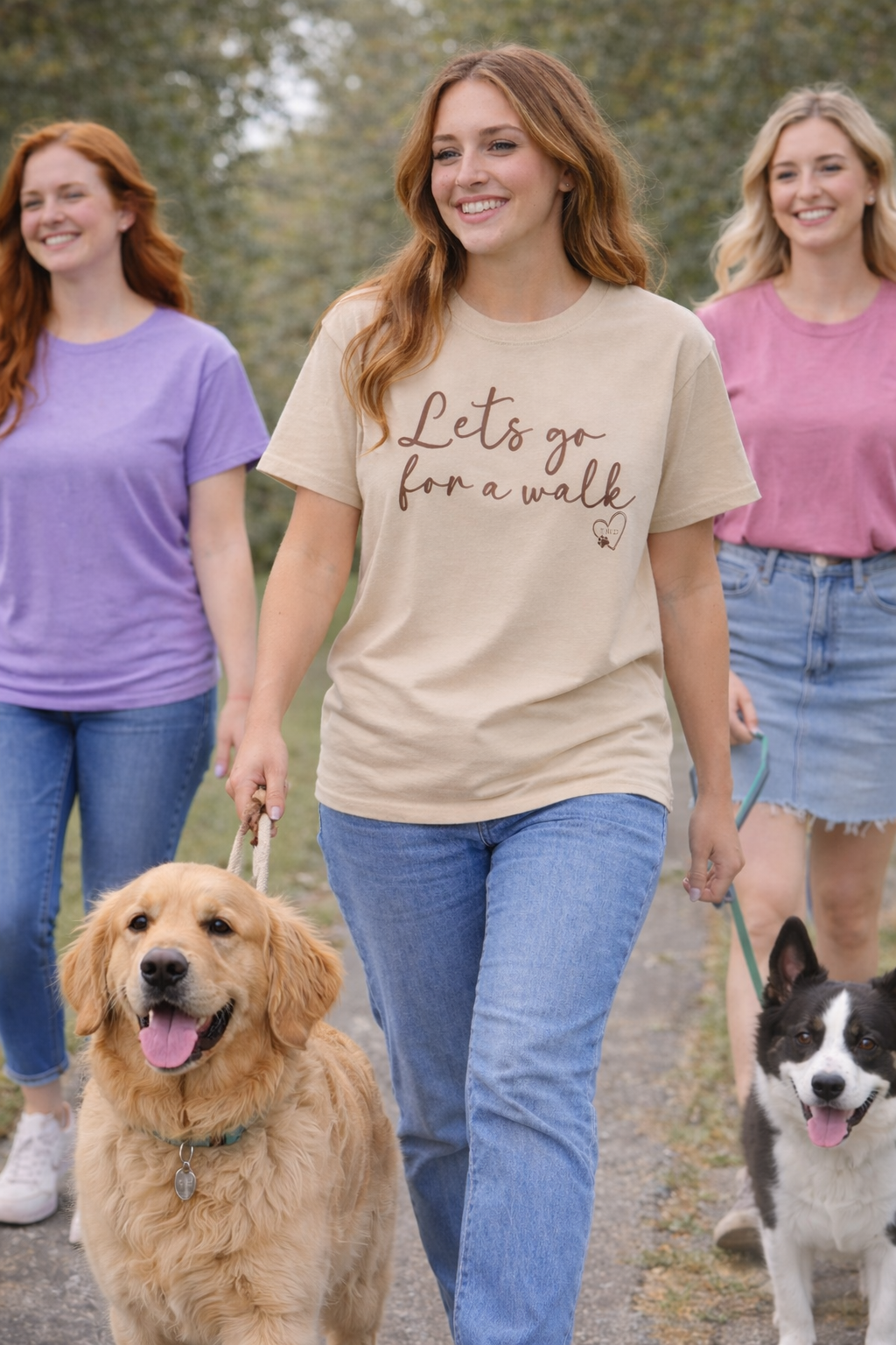 Three women walking dogs with one wearing a 'Let's go for a walk' shirt.